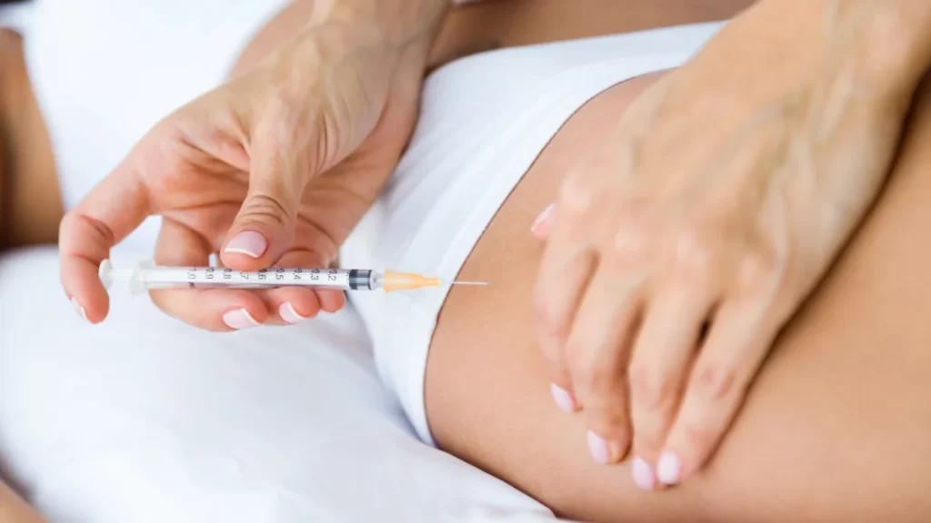 A woman receiving a medical injection in her abdomen, demonstrating a healthcare procedure in a clinical setting.