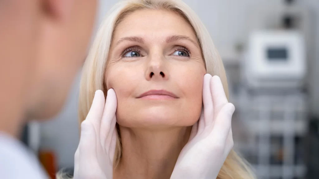 A woman receiving a facial examination from a doctor in a clinical setting.