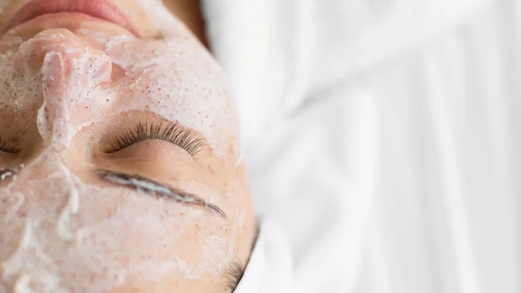A woman applying a facial mask as part of her skincare routine.