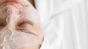 A woman applying a facial mask as part of her skincare routine.