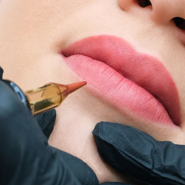 A woman receiving a lip tattoo, showcasing pigments used for permanent makeup application.
