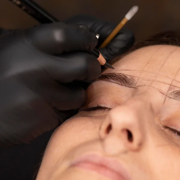 A woman receiving eyebrow micropigmentation in a beauty salon, focused on enhancing her eyebrow shape and color.